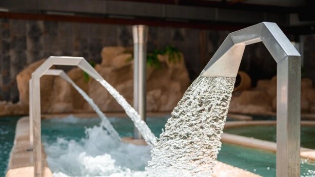 A water feature with two metal structures and water flowing from them into a pool.