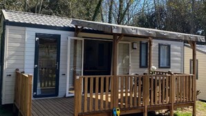 A mobile home with a wooden deck and a covered porch.