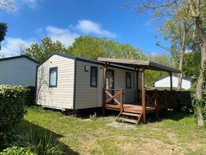A mobile home with a covered porch and a small deck.