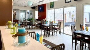 Interior de restaurante con mesas, sillas y farolillos de papel colgantes.