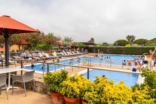 Ein Poolbereich mit mehreren Pools, Liegestühlen und Kübelpflanzen.