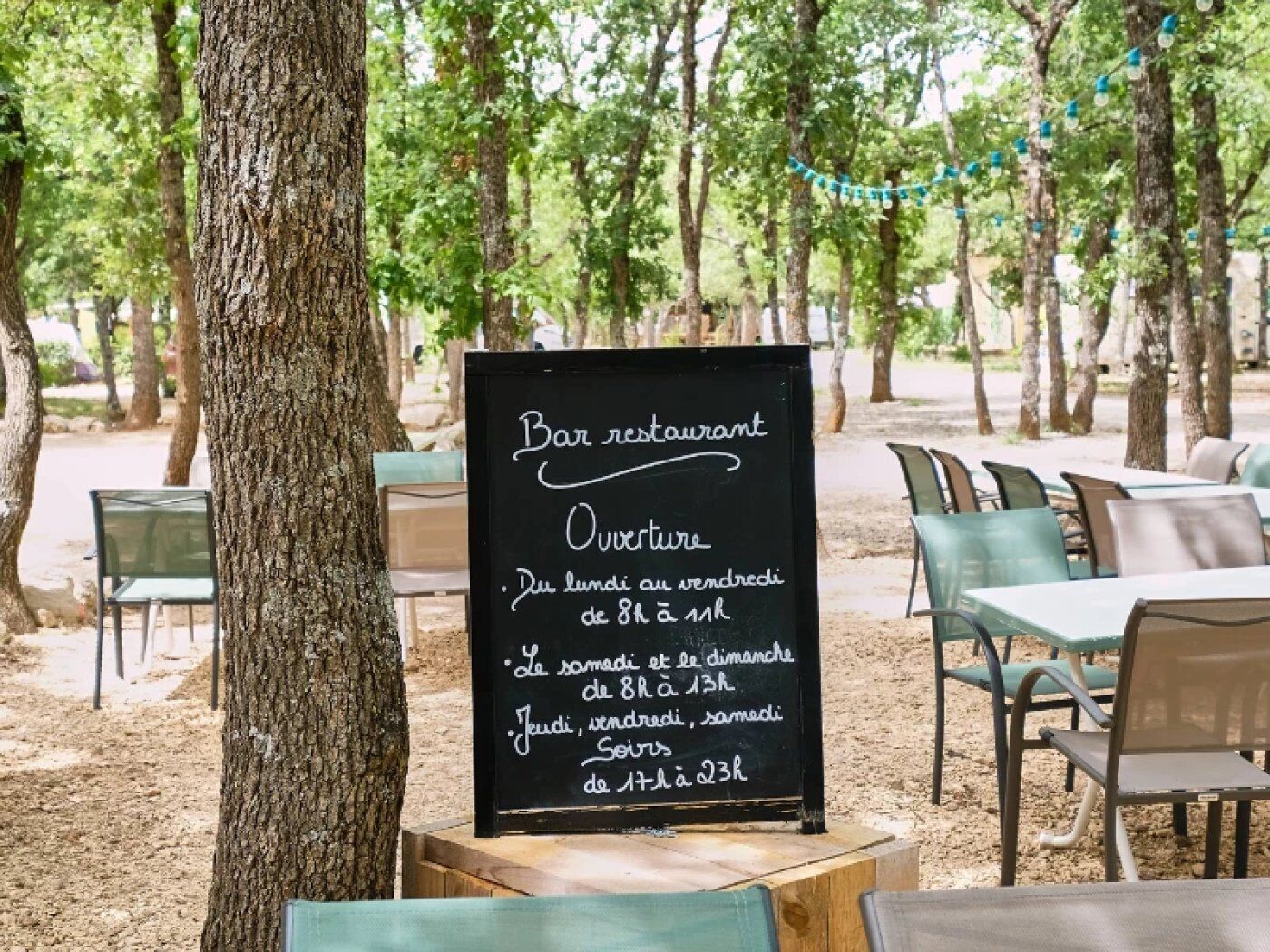 Restaurante al aire libre con una pizarra que muestra el horario de apertura.