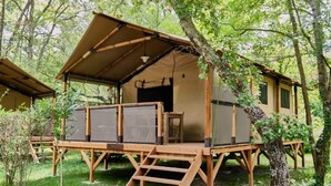 Een houten chalet met een overdekt terras, omringd door bomen.