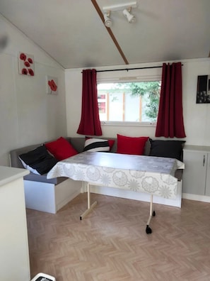 Een kleine kamer met een bed, een bureau en een raam met rode gordijnen.