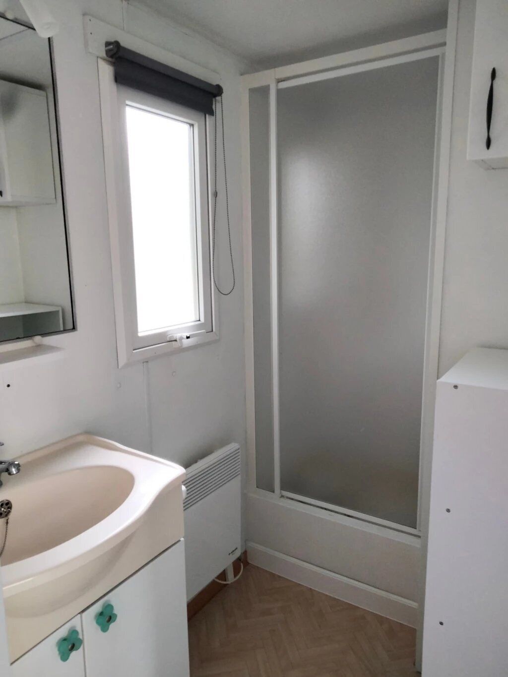 A small, clean bathroom with a sink, mirror, and window.