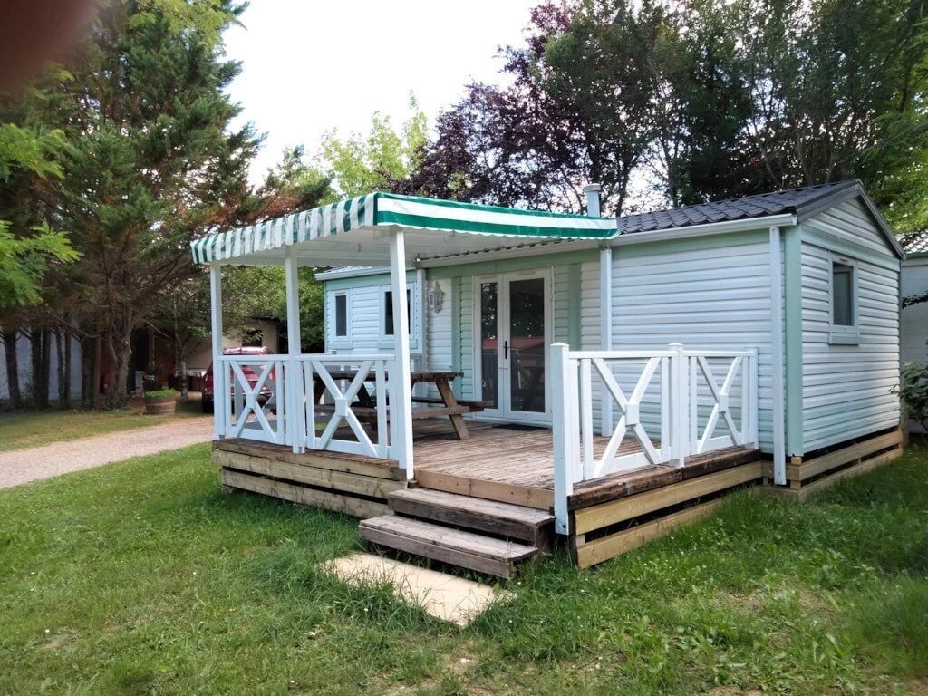 Uma cabana pequena, térrea, com varanda e mesa de piquenique.