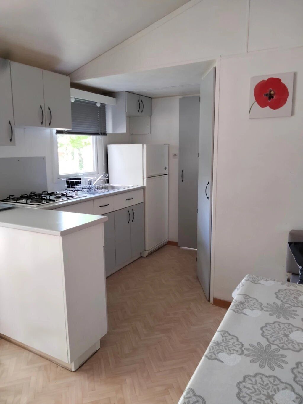 Una cocina compacta con muebles blancos, una isla central y un ventanal que proporciona luz natural.