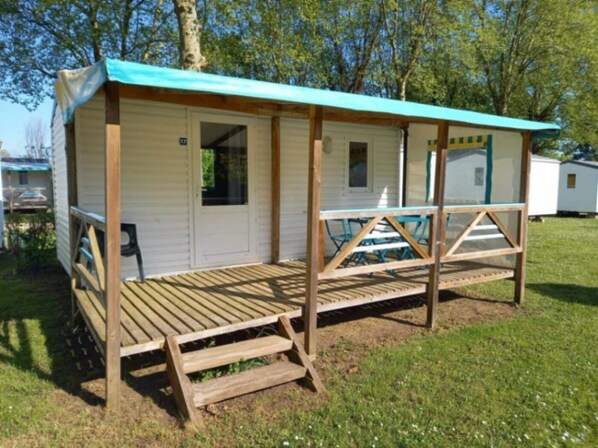 A mobile home with a covered porch and a small deck.