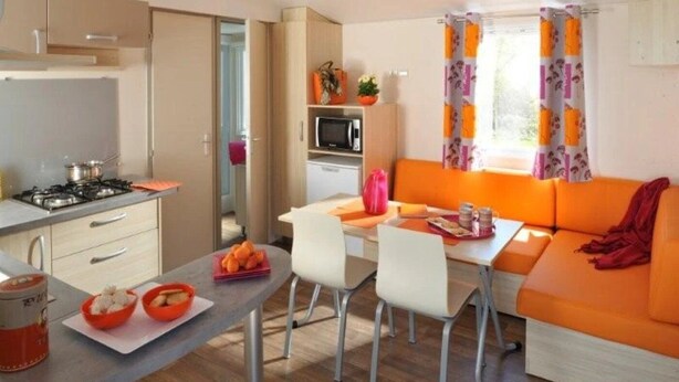 Una cocina compacta con estufa, microondas y comedor con mesa y sillas.