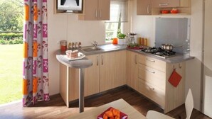Una cocina moderna con armarios de madera, una estufa integrada y una ventana con vistas a un jardín.