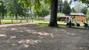Une zone recouverte de gravier, avec un arbre, une clôture en bois et un bâtiment doté d’un toit rouge.