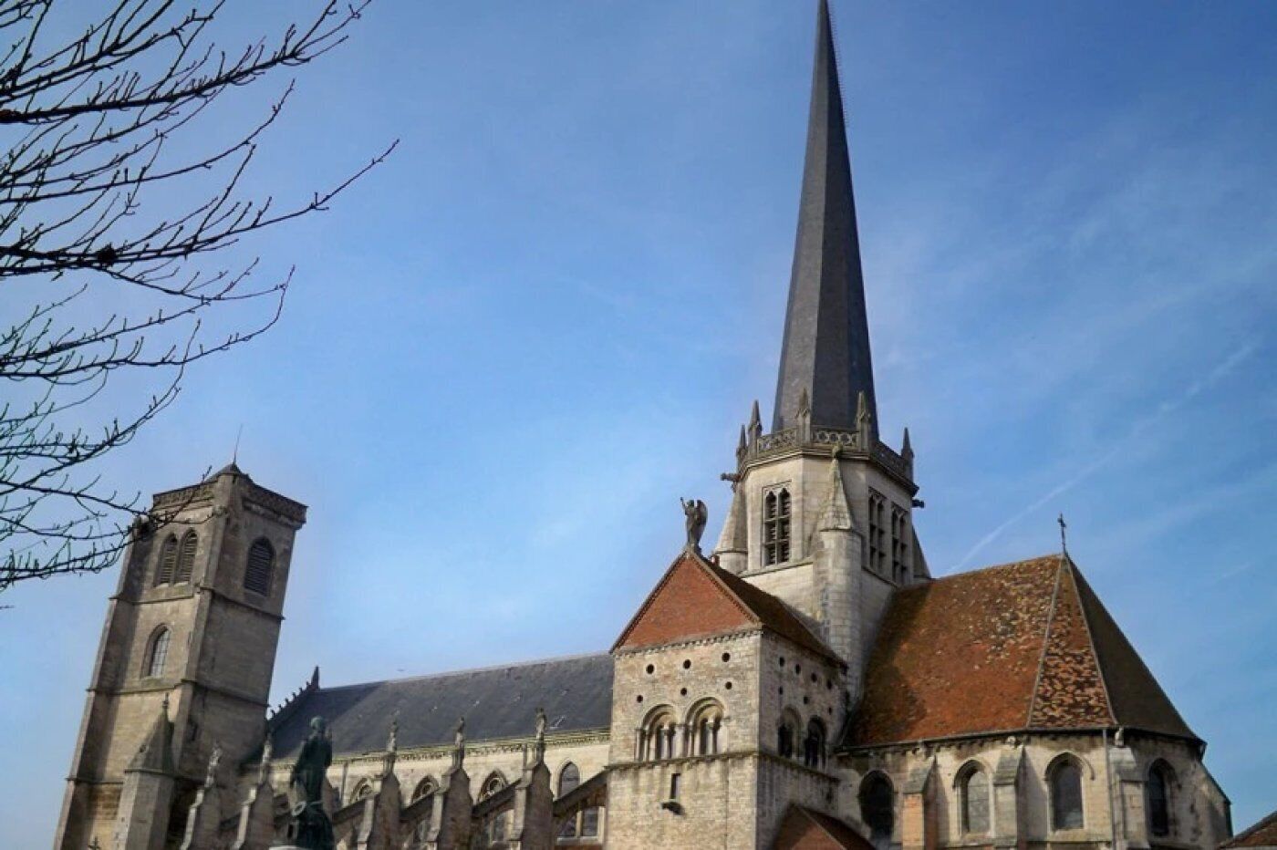 A church with a tall spire and a smaller tower, featuring arched windows and a stone facade.