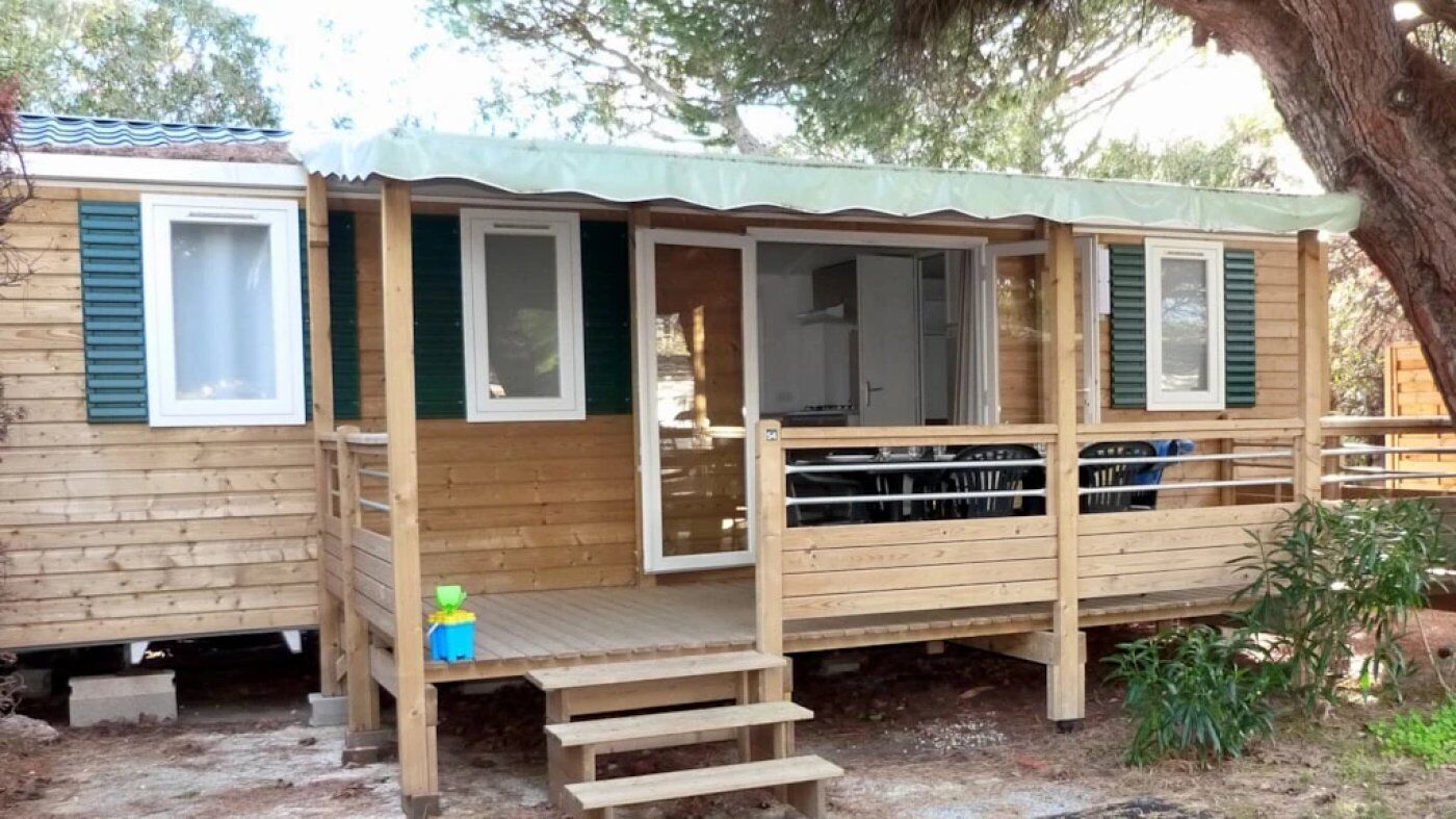 A wooden cabin with a deck, a covered porch, and a small outdoor area.
