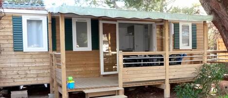 A wooden cabin with a deck, a covered porch, and a small outdoor area.