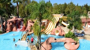 Una piscina con tobogán y formaciones rocosas.