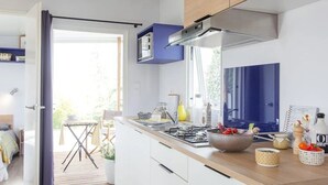 A modern kitchen with white cabinets, a wooden countertop, and a built-in stove. - ZEcamping 3* avec piscine chauffée club enfant animations pet friendly (Erquy)