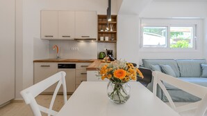 Eine moderne Küche mit weißen Schränken, einer Holztischplatte und einem Esstisch mit Blumen in einer Vase.