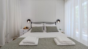 Ein ordentlich eingerichtetes Schlafzimmer mit Bett, Nachttischen und einem Fenster mit Vorhängen.