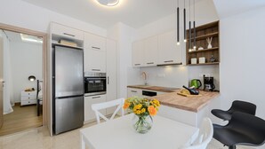 Eine moderne Küche mit weißen Schränken, einem Edelstahlkühlschrank, einer Holz Arbeitsplatte und einem Essbereich mit weißem Tisch und Stühlen.
