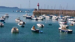 Un port de plaisance où sont amarrés de nombreux bateaux, un phare et une digue rocheuse.