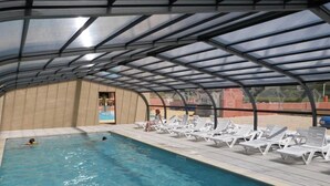 An indoor swimming pool with a covered roof, lounge chairs, and a view of the pool area. - ZEcamping 3* piscine couverte animations locatif TV 28m2 4 pers (Erquy)