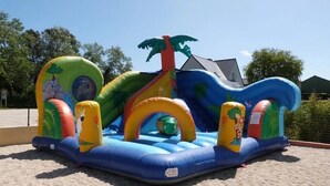 An inflatable play structure with slides, tunnels, and a slide with a dinosaur theme. - ZEcamping 3* animé piscine couverte chiens acceptés locatif TV 30m2 (Erquy)