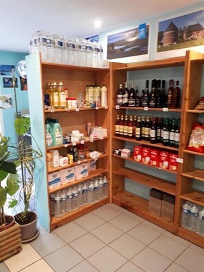 A store with shelves stocked with various beverages, including bottled water, milk, and alcoholic drinks.