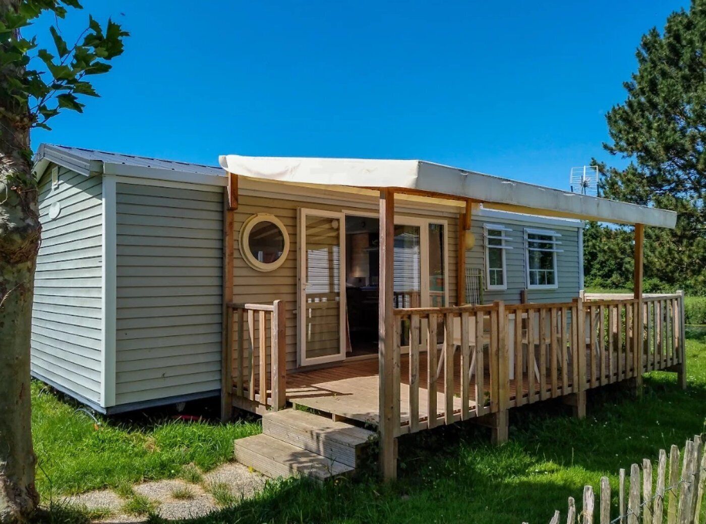 A small, single-story cabin with a wooden deck and a covered porch.