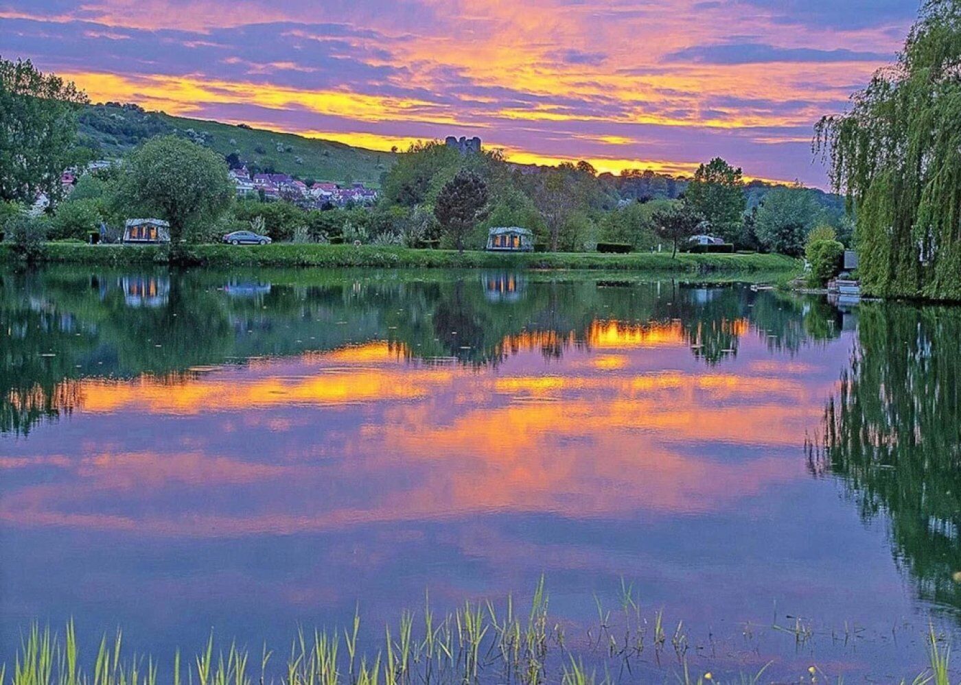 Un lago tranquilo con reflejos de árboles y un cielo al atardecer.