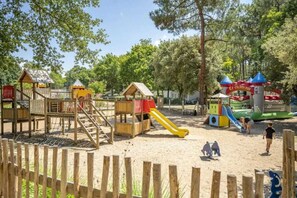 Explore a playground with a climbing frame, slide, and playhouse, surrounded by trees.