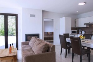 Un espacio habitable moderno con sofá, mesa de comedor, sillas, zona de cocina y chimenea.