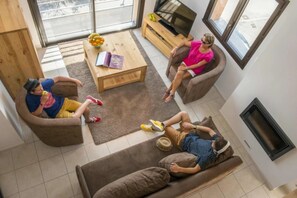 A modern living room with a sofa, a coffee table, and a TV. - ZEcamping 3 étoiles pataugeoire club enfant locatif TV LV clim 90m2 (Le Sauze-du-Lac)