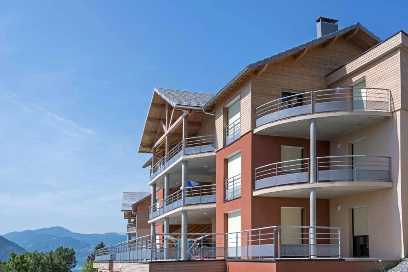 A multi-story hotel with balconies and a view of mountains.
