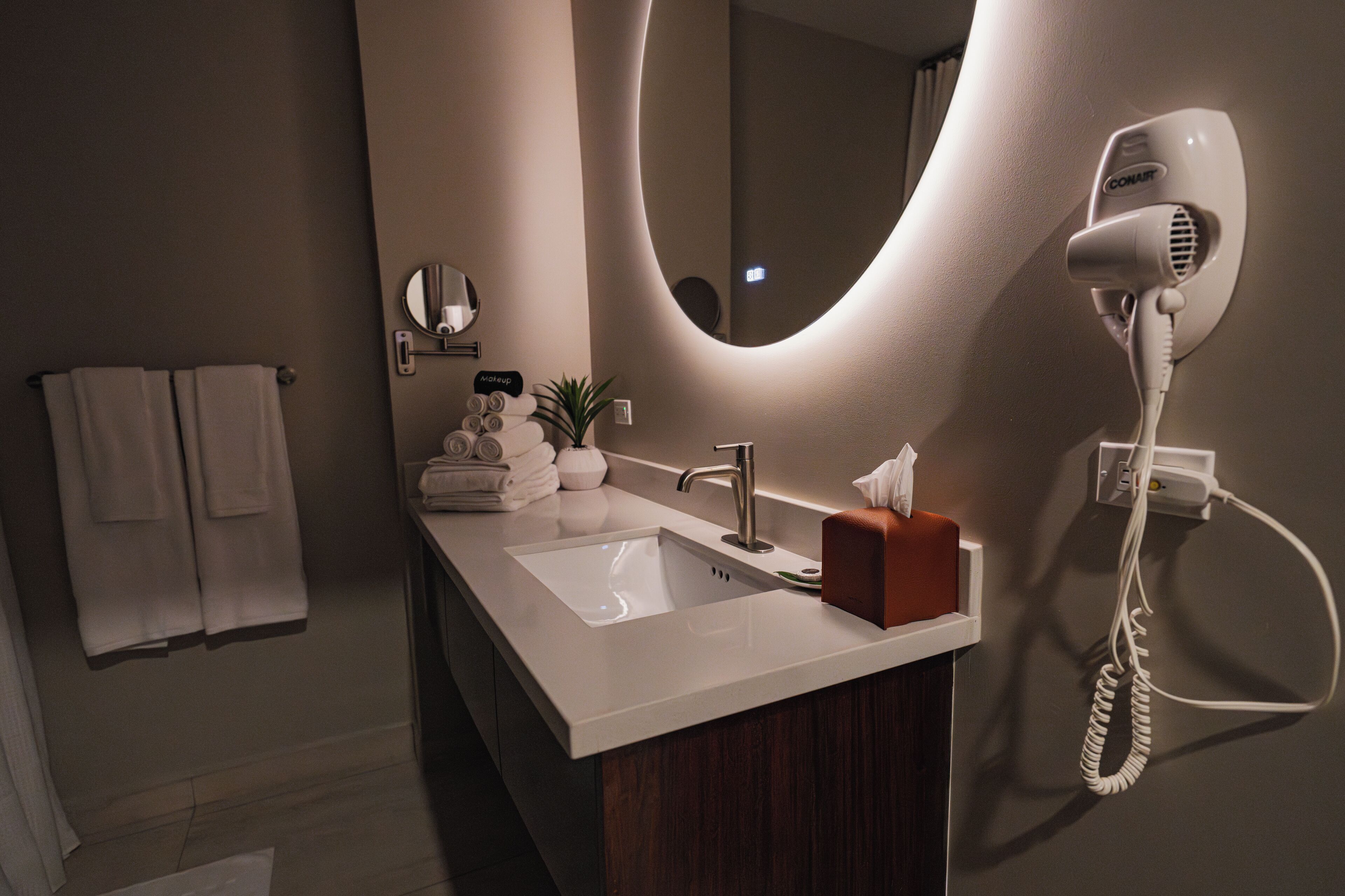 A modern bathroom with a sink, a hairdryer, a mirror, and a towel rack.