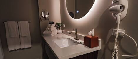 A modern bathroom with a sink, a hairdryer, a mirror, and a towel rack.
