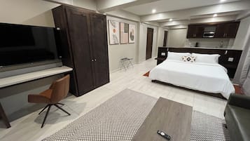 Una camera d'albergo moderna con un letto, una scrivania, una TV e un angolo cottura.