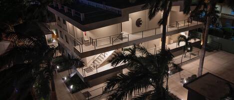 A multi-story building with balconies, staircases, and palm trees.