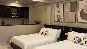 Ein modernes Schlafzimmer mit zwei Betten, einer Küchenzeile und Bildern an den Wänden.