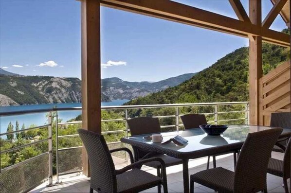 Comedor con mesa y sillas con vistas panorámicas a un lago y montañas.