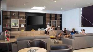 Ein modernes Wohnzimmer mit einem großen Flachbildfernseher, bequemen Sitzmöglichkeiten und einem Couchtisch.