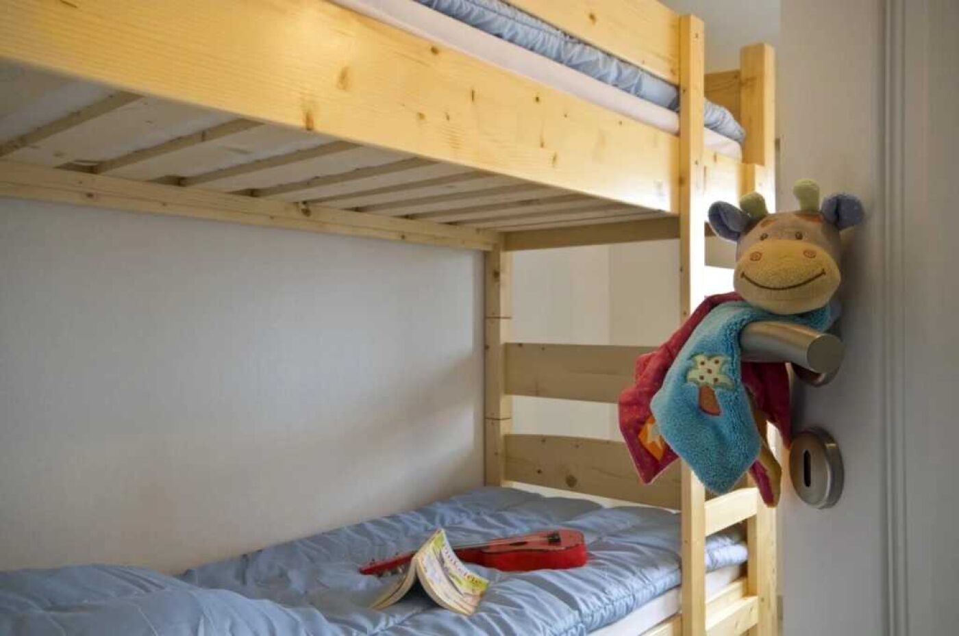 A bunk bed with a stuffed toy hanging on the door.