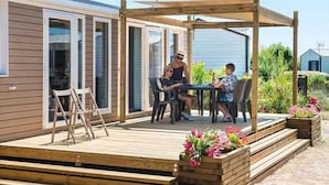 Puinen terassi, jossa on pergola, pöytä ja tuoleja.