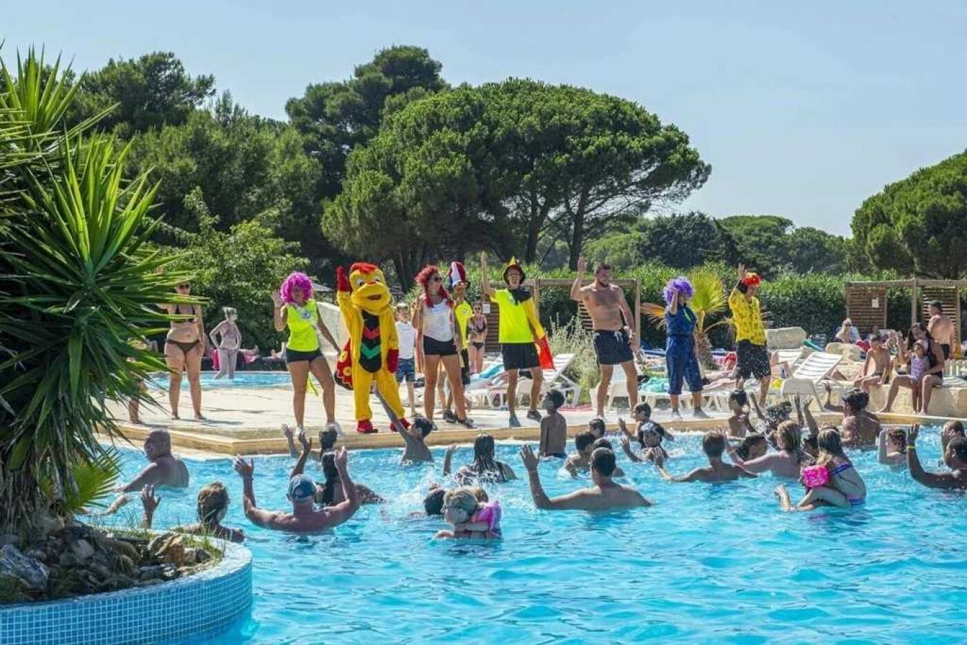 Ein Schwimmbecken mit Personen und Maskottchen.
