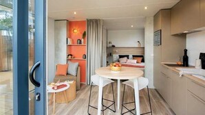 A compact kitchen with a round dining table, a small bar area, and a sofa in the background.