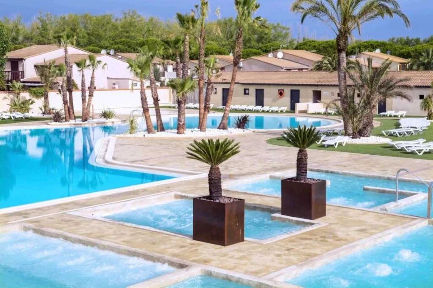A swimming pool with palm trees and lounge chairs.