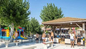 An outdoor area with a playground, benches, and a covered seating area.