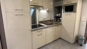 A compact kitchen with a built-in stove, microwave, and stainless steel range hood. - ZEcamping piscine couverte dog friendly animations locatif LV BBQ (Léon)