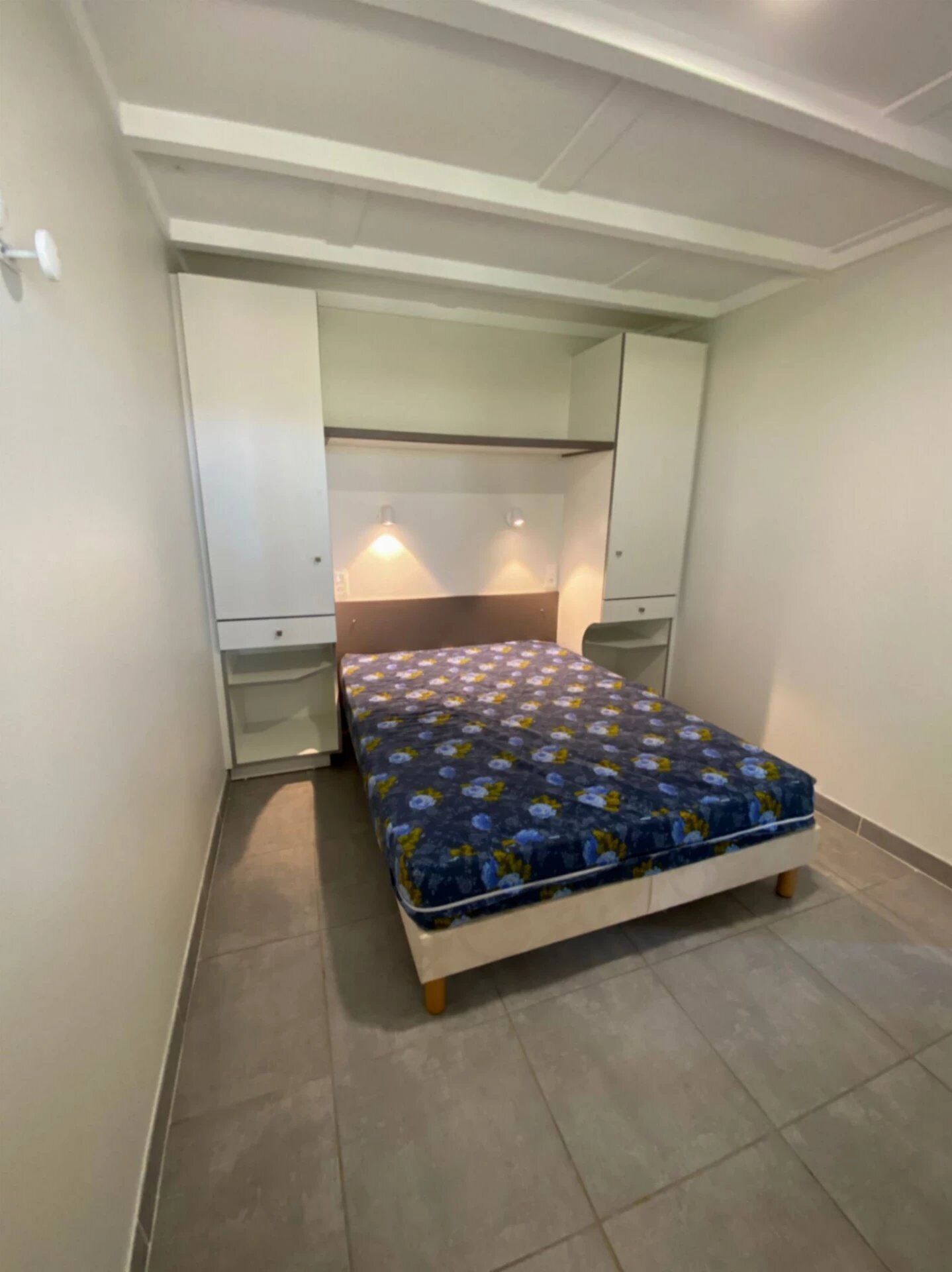 A small bedroom with a single bed, a wardrobe, and a mirror.