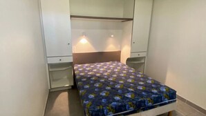 A small bedroom with a single bed, a wardrobe, and a mirror. - ZEcamping piscine couverte dog friendly animations locatif LV BBQ (Léon)