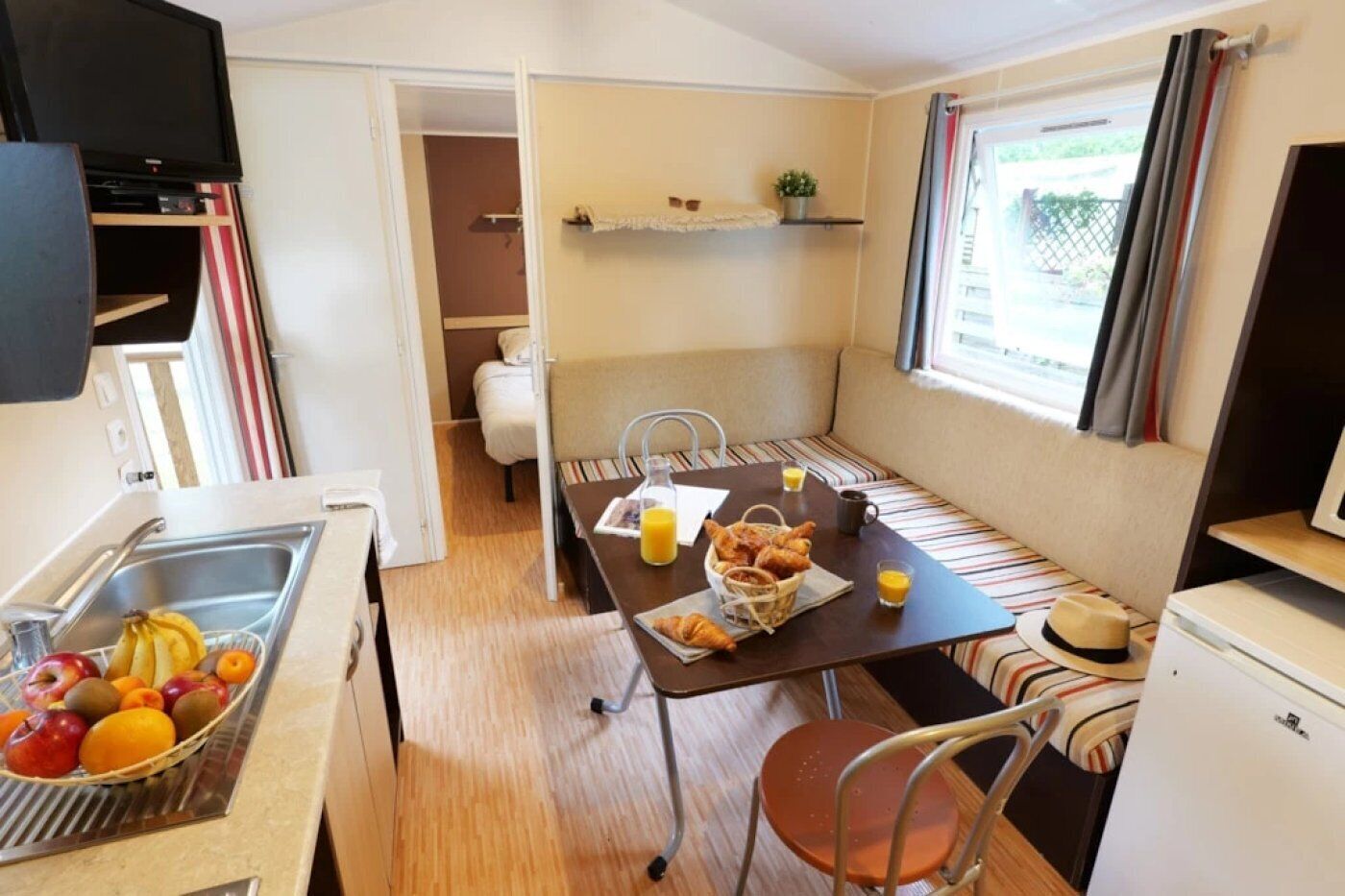 A compact kitchenette with a sink, a small fridge, and a dining area with a table set for breakfast.